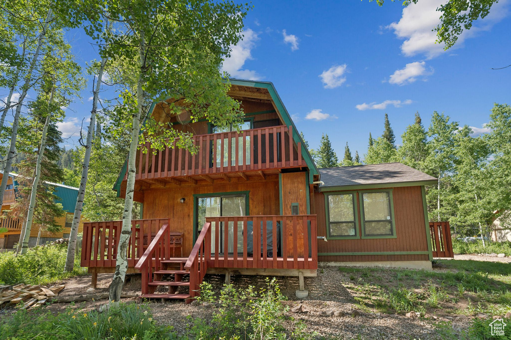 Rear view of property featuring a shingled roof and a deck