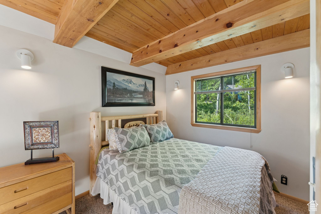 Bedroom featuring carpet flooring, wood ceiling with exposed beams, and baseboards