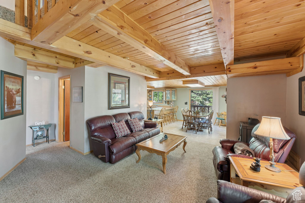 Carpeted living area with wooden ceiling with exposed beams and baseboards