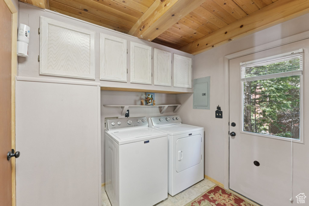 Washroom with washing machine and clothes dryer, cabinet space, electric panel, and wood ceiling