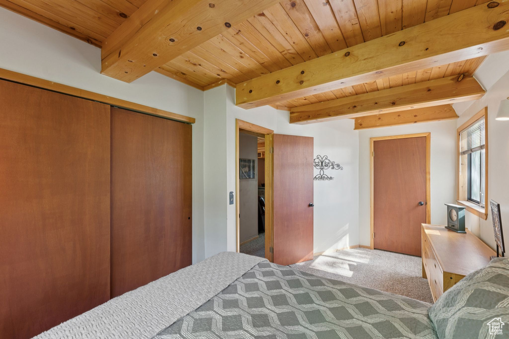 Carpeted bedroom with wood ceiling with exposed beams and a closet
