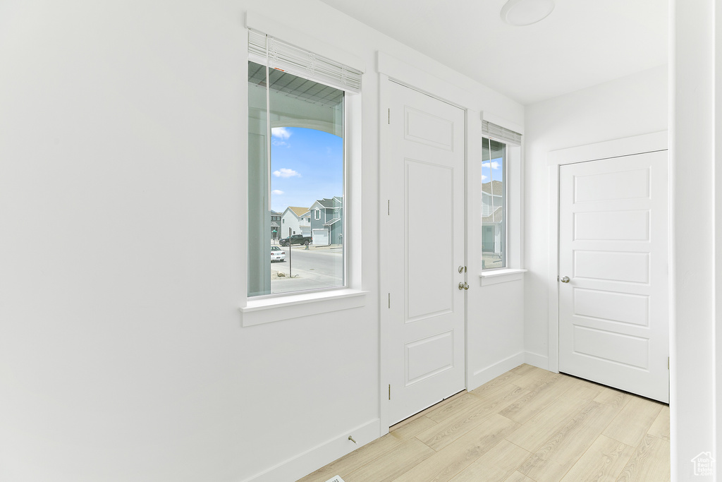Doorway with light wood finished floors and baseboards