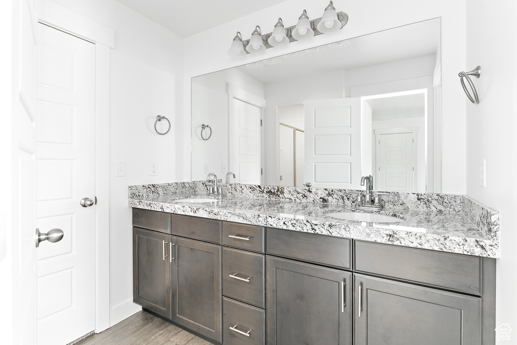 Bathroom featuring double vanity, wood finished floors, and an enclosed shower