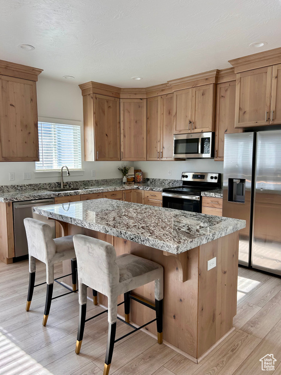 Kitchen featuring stainless steel appliances, light wood-type flooring, a kitchen island, a kitchen breakfast bar, and recessed lighting