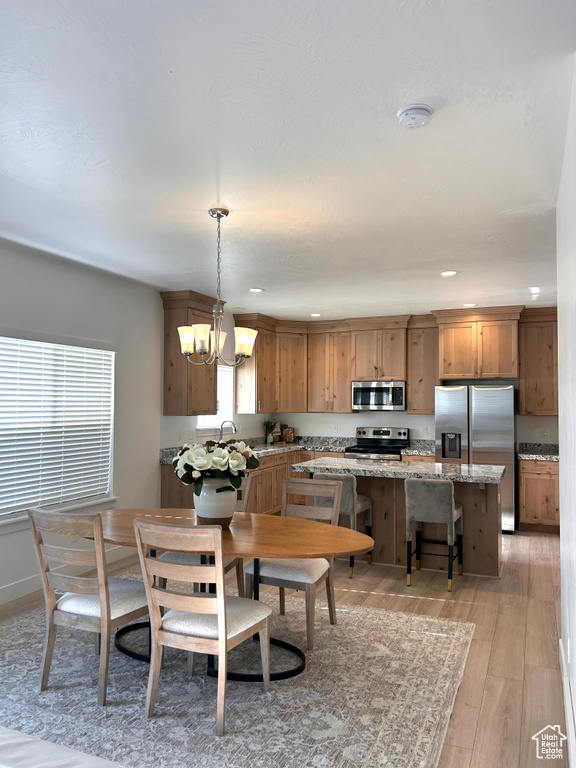 Dining room with a chandelier, light wood finished floors, and recessed lighting