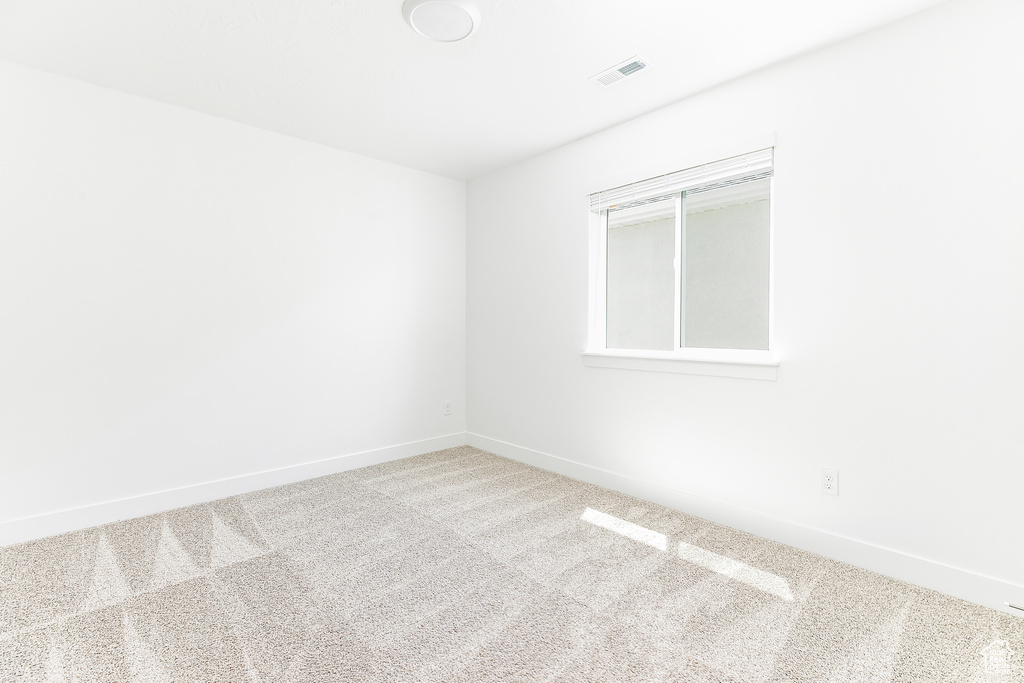Carpeted spare room featuring baseboards