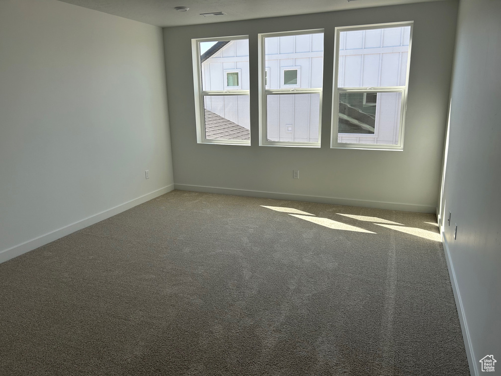 Carpeted spare room featuring baseboards