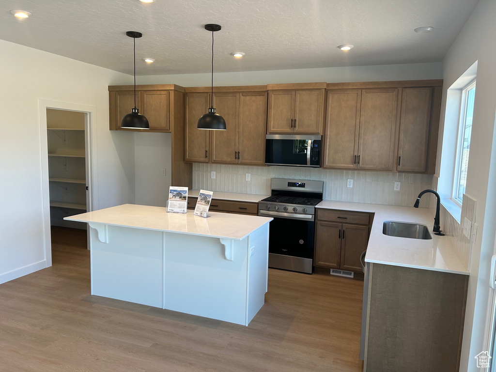 Kitchen featuring appliances with stainless steel finishes, light wood-style floors, backsplash, light countertops, and recessed lighting
