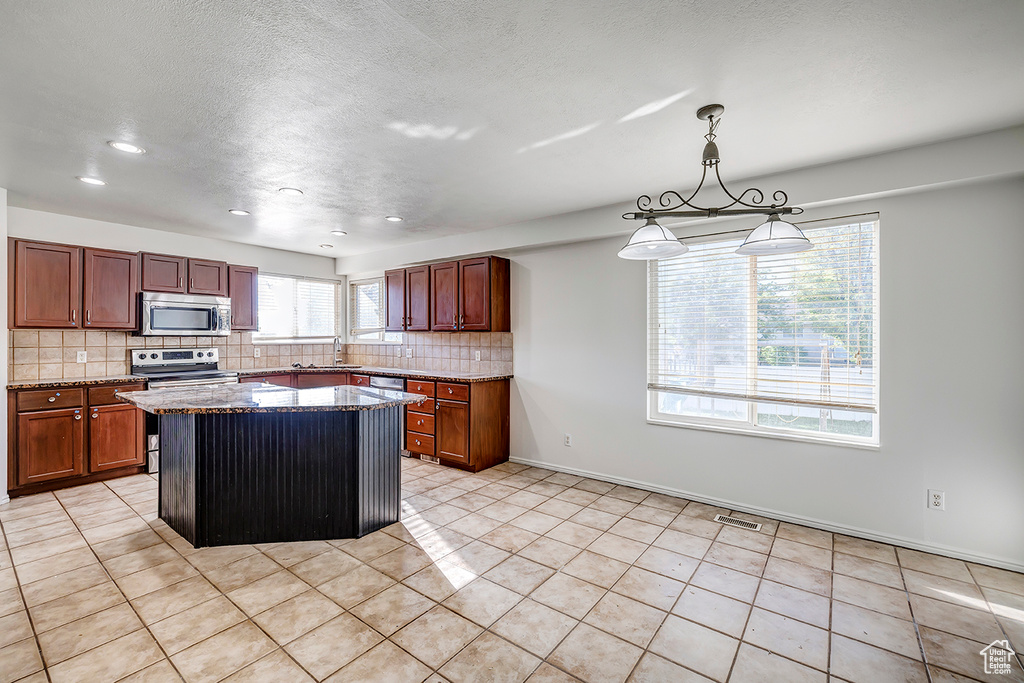 Kitchen with appliances with stainless steel finishes, tasteful backsplash, dark stone countertops, recessed lighting, and light tile patterned floors