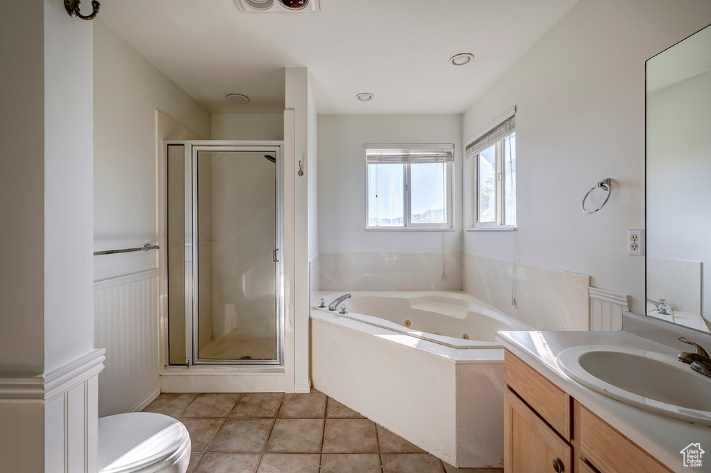Bathroom featuring a tub with jets, vanity, a shower stall, wainscoting, and tile patterned flooring