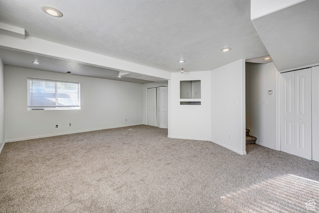 Below grade area with carpet flooring, recessed lighting, stairs, and a textured ceiling