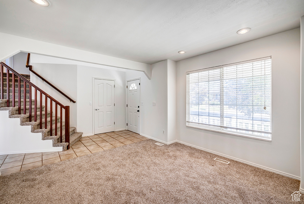 Carpeted foyer with stairs, tile patterned flooring, and recessed lighting