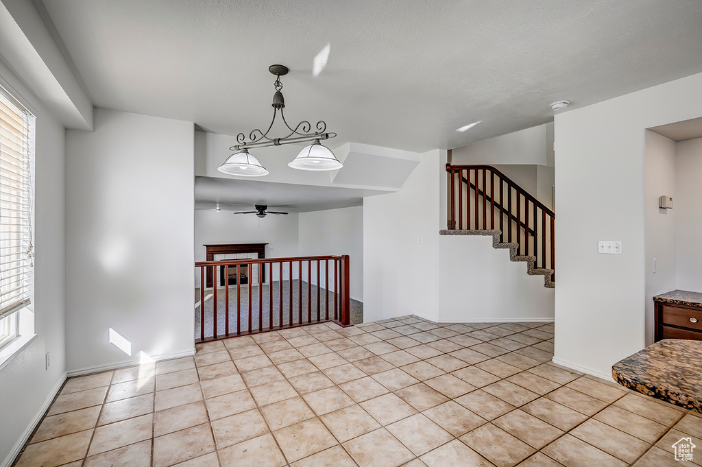 Unfurnished room with light tile patterned flooring, a ceiling fan, a smoke detector, and stairway