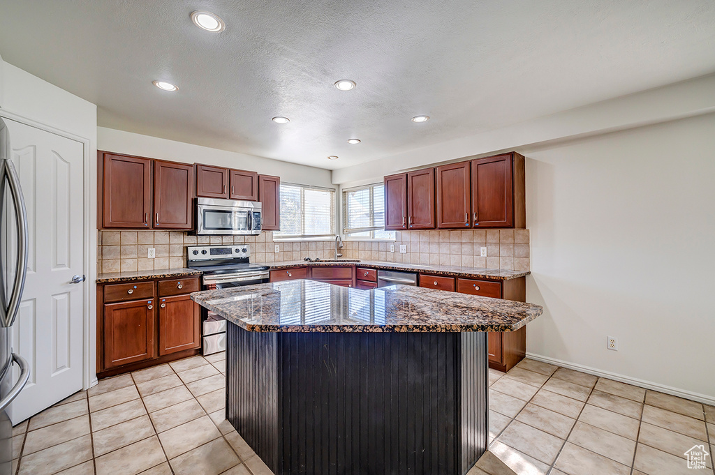 Kitchen with stainless steel appliances, dark stone counters, tasteful backsplash, recessed lighting, and light tile patterned floors