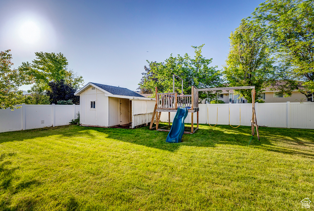 Fenced backyard with a playground and a shed