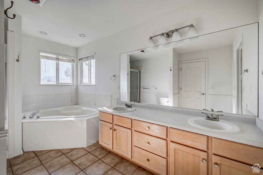 Full bathroom with a bath, double vanity, a shower stall, and tile patterned flooring