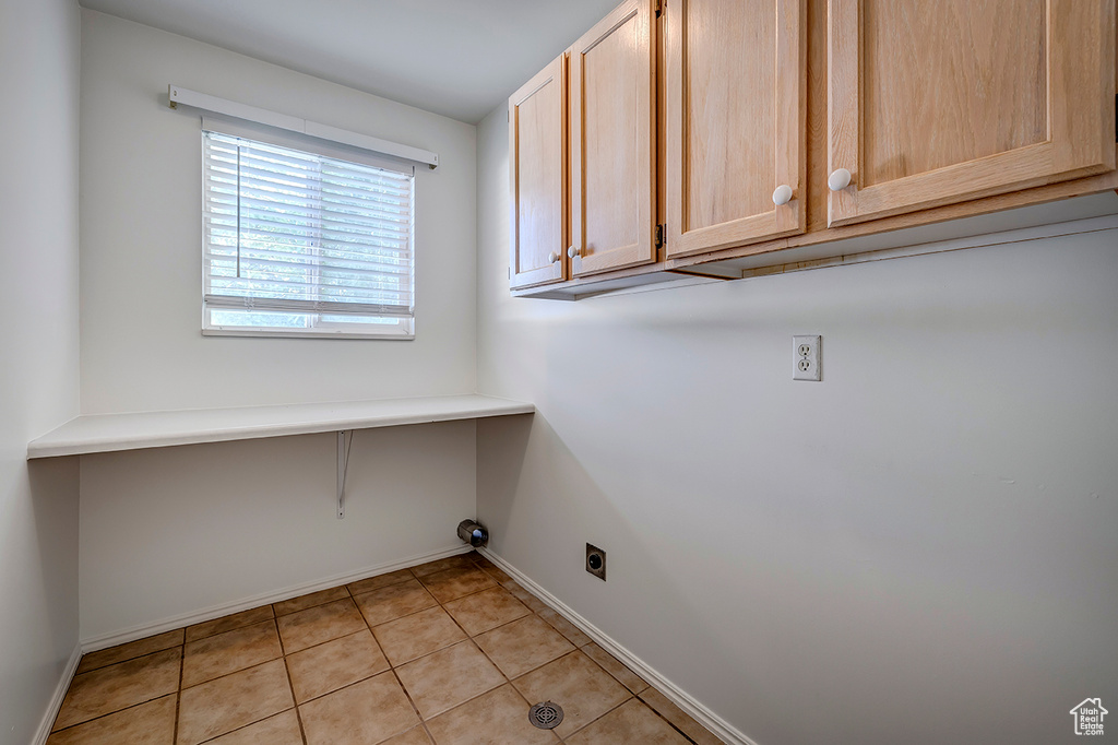 Laundry room featuring cabinet space, hookup for an electric dryer, and light tile patterned floors