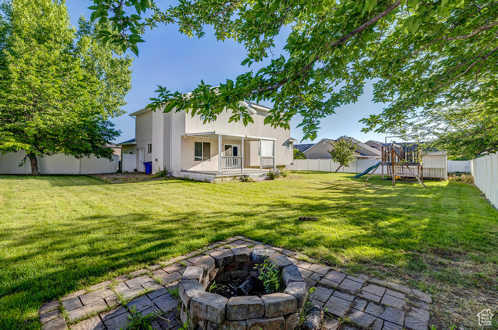 Fenced backyard with a playground and an outdoor fire pit
