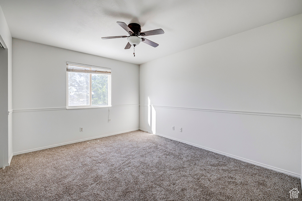 Carpeted spare room with ceiling fan and baseboards