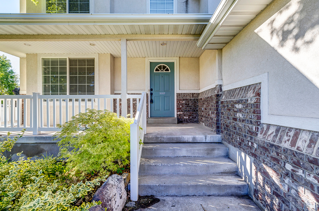 Property entrance featuring stucco siding and covered porch