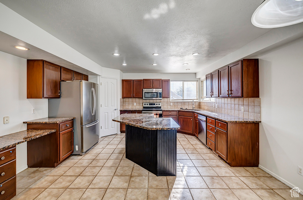 Kitchen featuring stainless steel appliances, tasteful backsplash, a kitchen island, recessed lighting, and stone counters