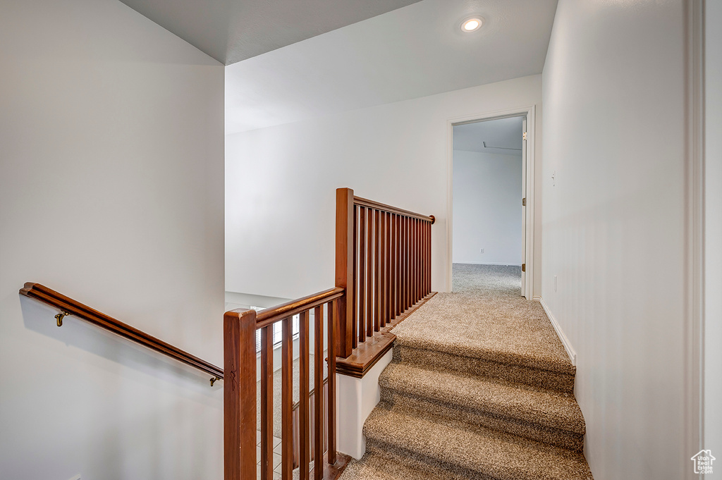 Stairs with carpet flooring and recessed lighting