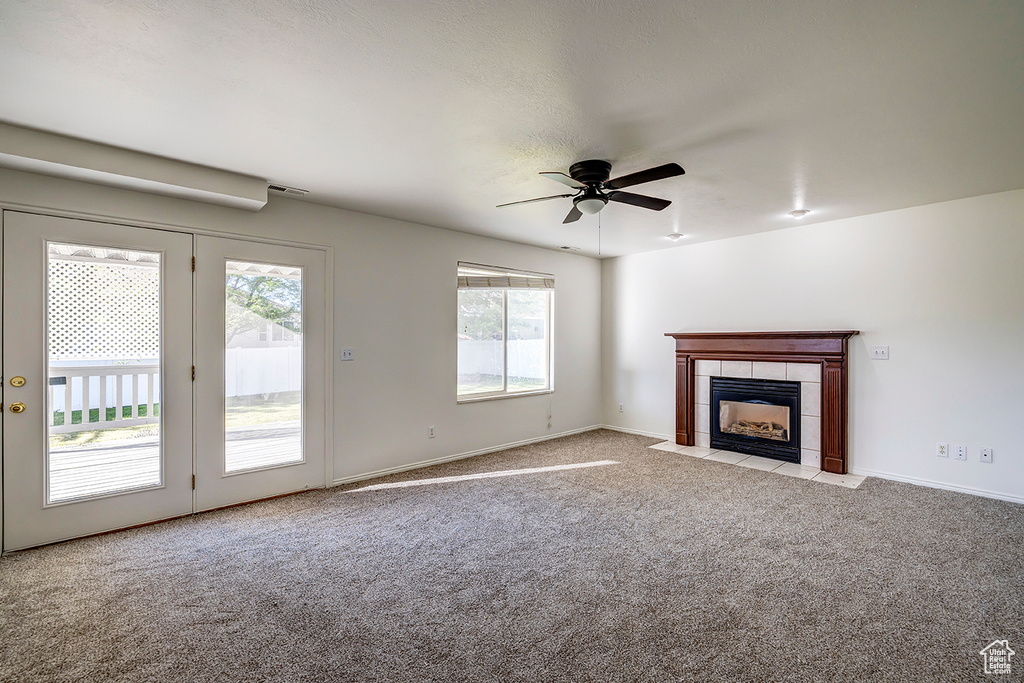 Unfurnished living room with carpet floors, healthy amount of natural light, ceiling fan, and a fireplace