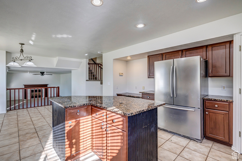Kitchen with freestanding refrigerator, a ceiling fan, light tile patterned flooring, dark stone counters, and recessed lighting