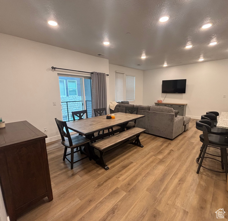 Dining room featuring light wood-style flooring, recessed lighting, baseboards, and a textured ceiling