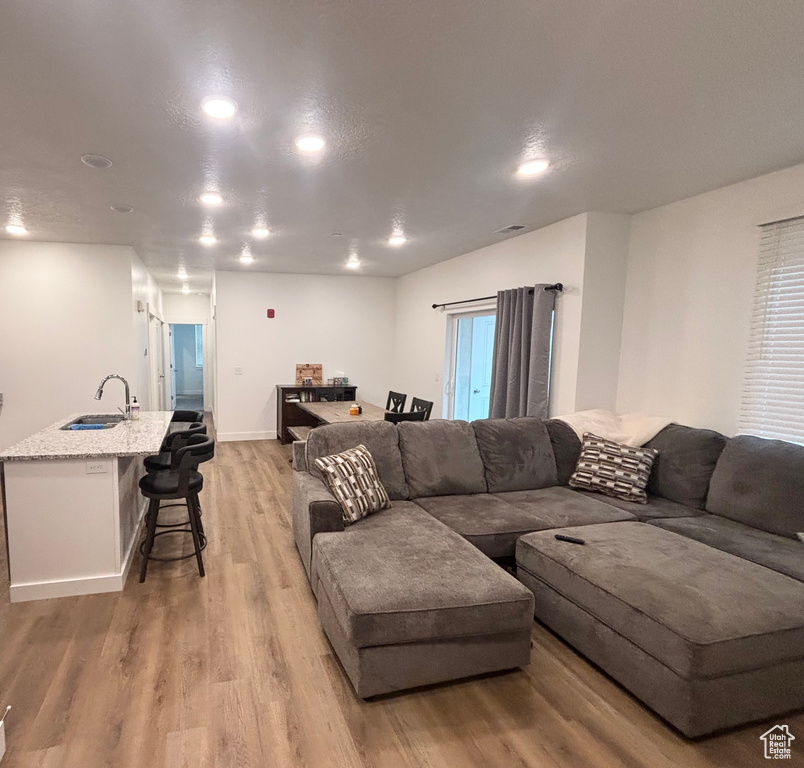 Living room featuring light wood-type flooring, recessed lighting, and baseboards