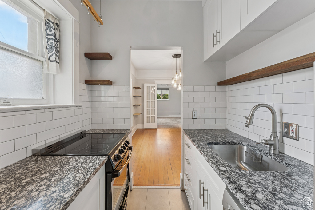 Kitchen with open shelves, electric stove, backsplash, and white cabinets