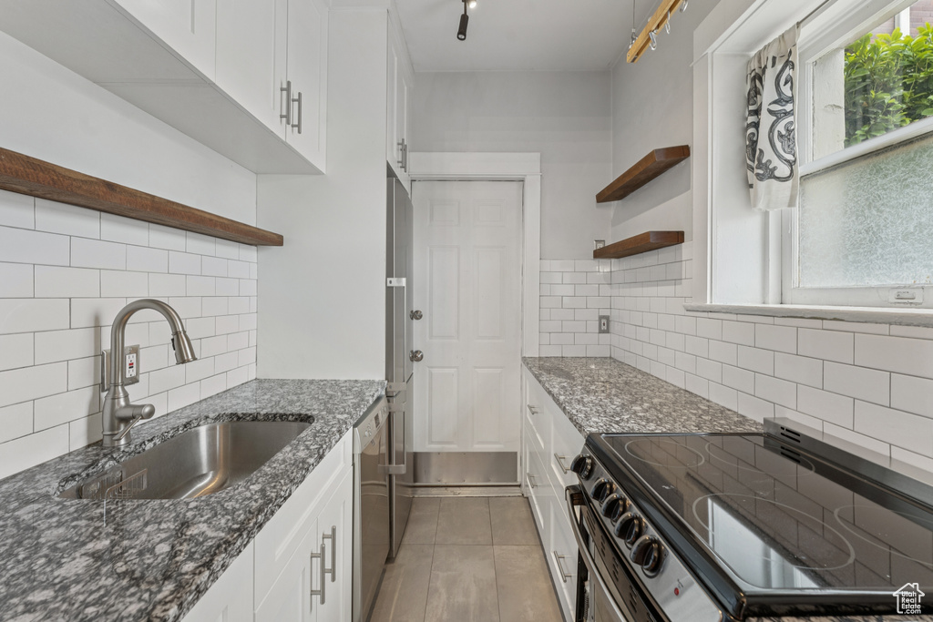 Kitchen featuring open shelves, appliances with stainless steel finishes, tasteful backsplash, and white cabinetry