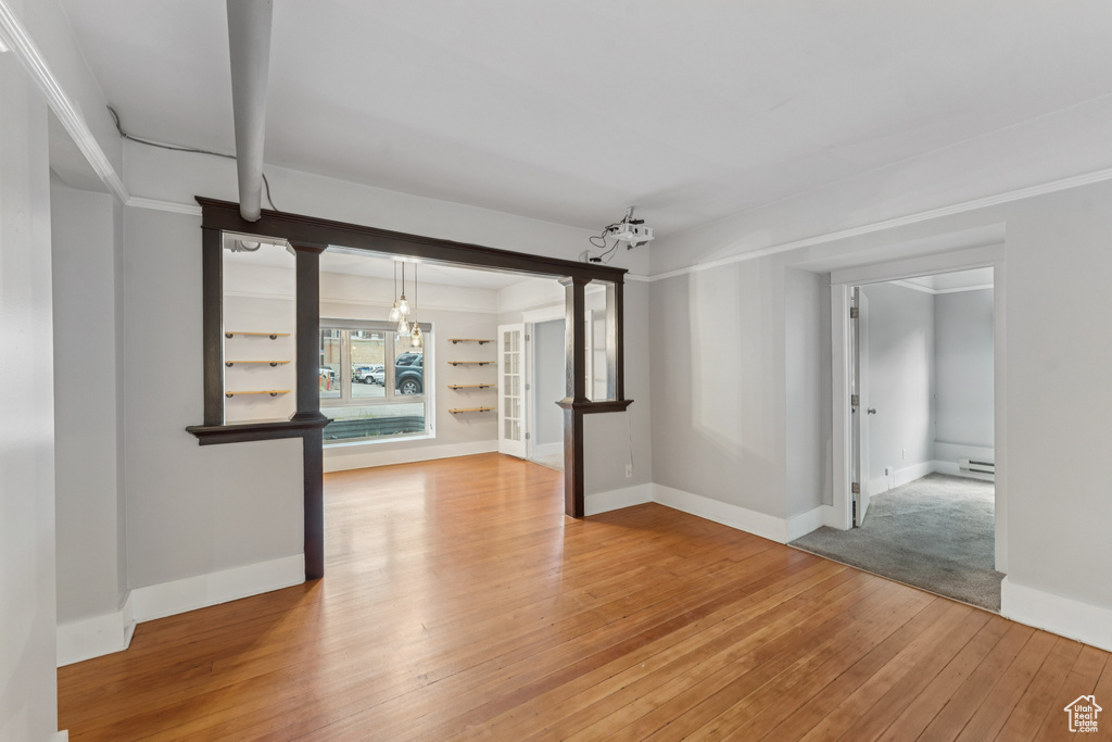 Unfurnished room with light wood-type flooring, a baseboard heating unit, and a chandelier