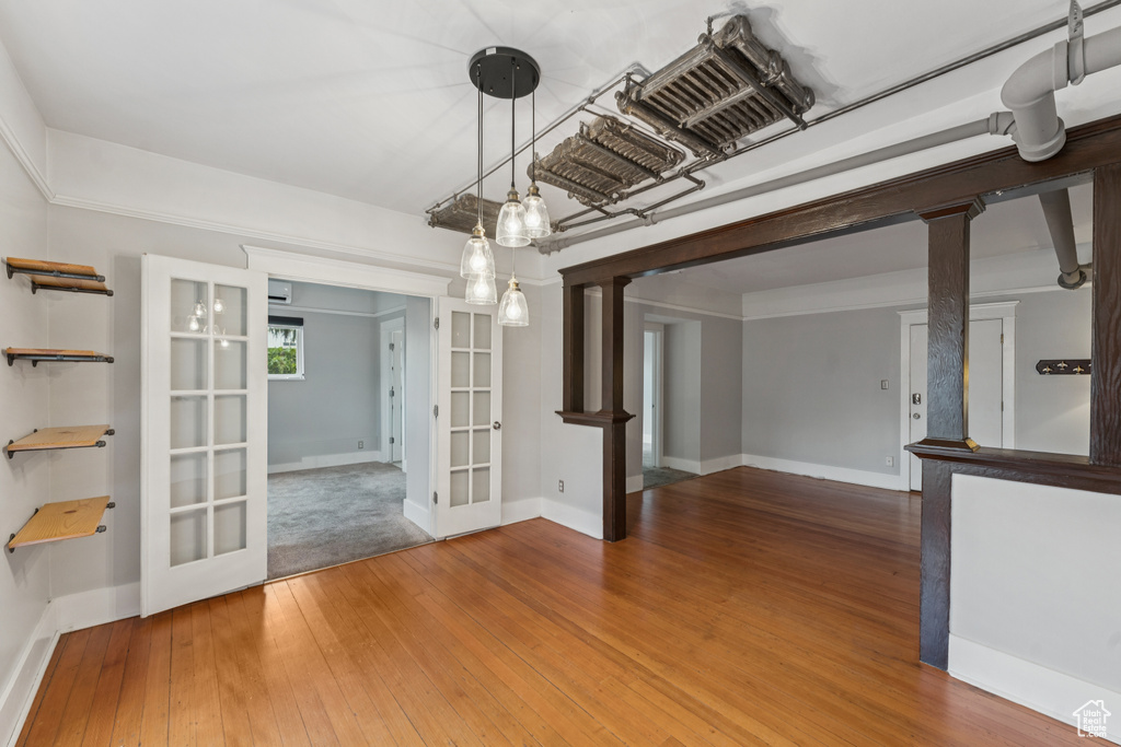 Unfurnished dining area featuring french doors, decorative columns, and hardwood / wood-style flooring