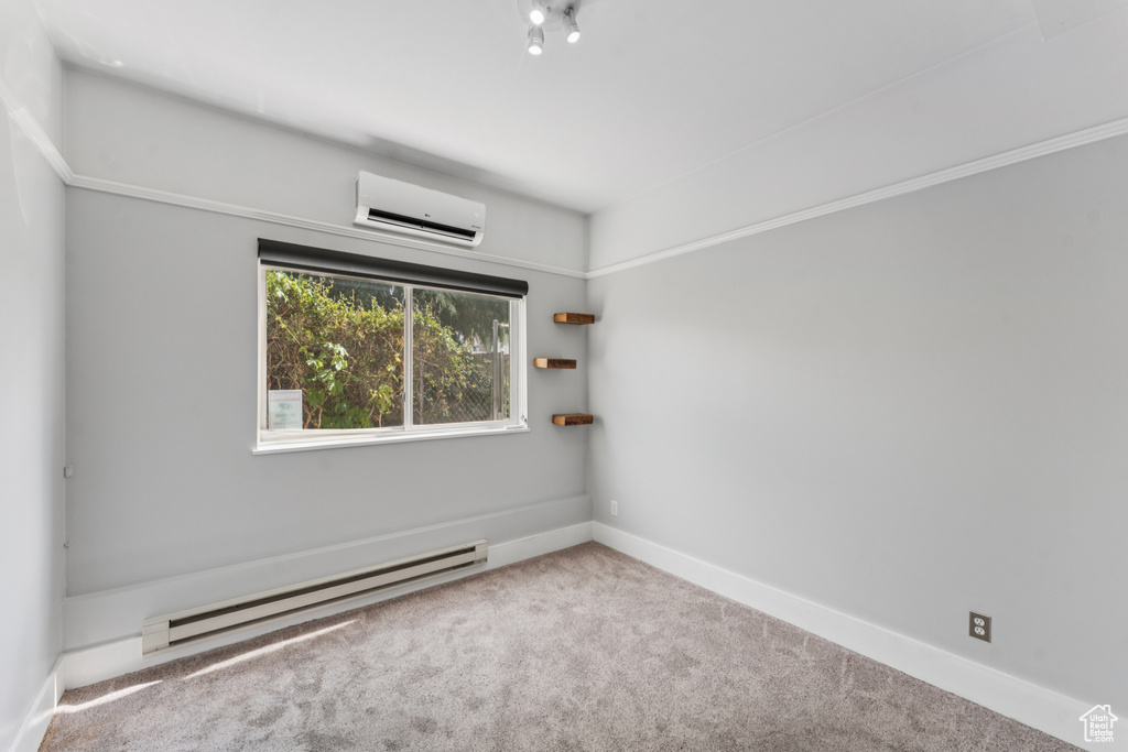 Carpeted spare room featuring a baseboard radiator and an AC wall unit