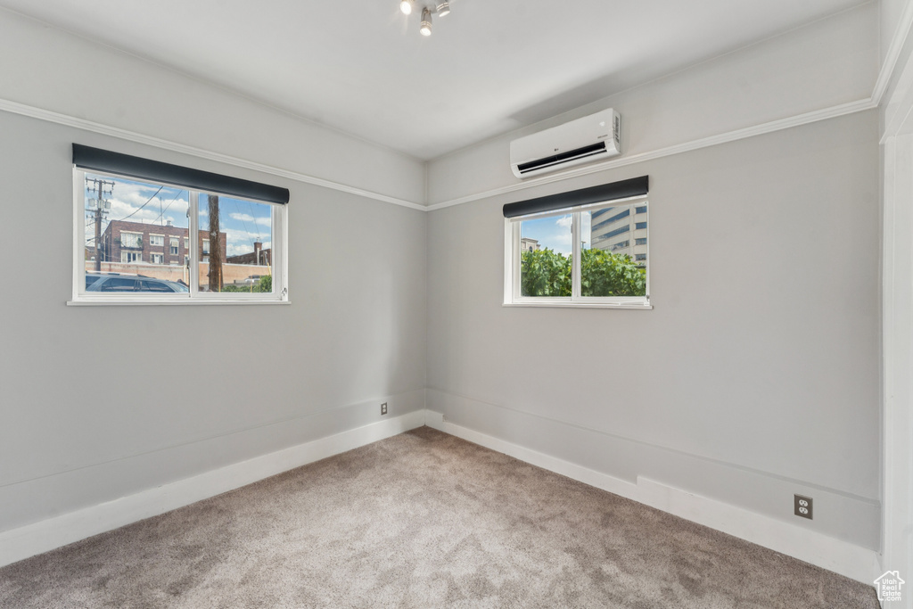 Unfurnished room featuring a wall mounted air conditioner and carpet floors