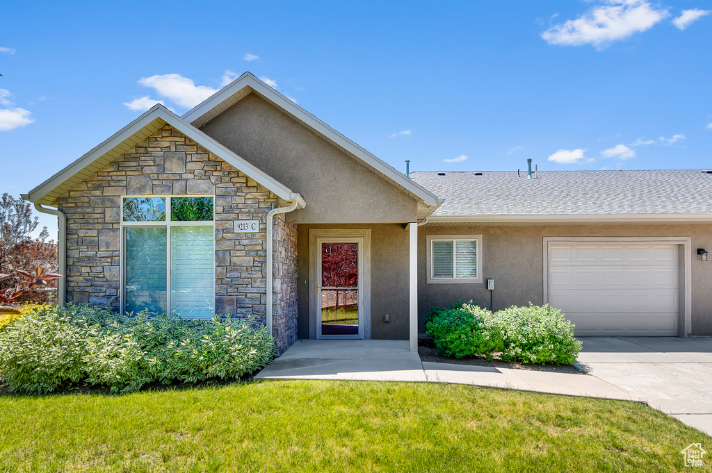 View of front of property featuring stone siding, stucco siding, an attached garage, and a front yard