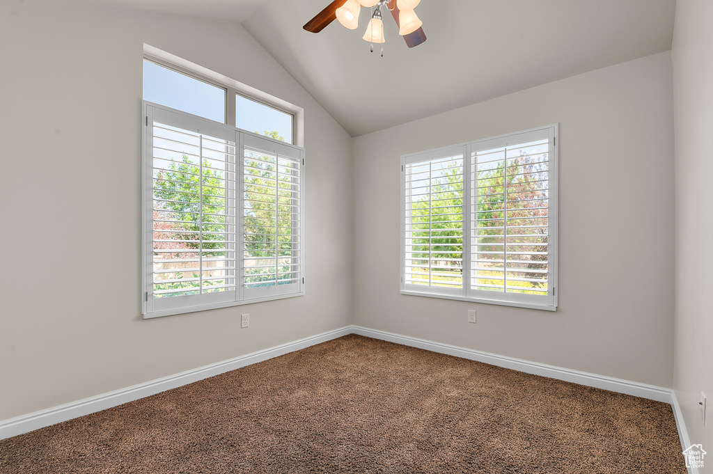 Spare room featuring carpet floors, lofted ceiling, and a ceiling fan