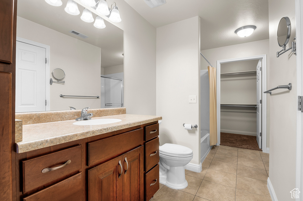 Full bathroom featuring curtained shower, vanity, tile patterned flooring, and a spacious closet