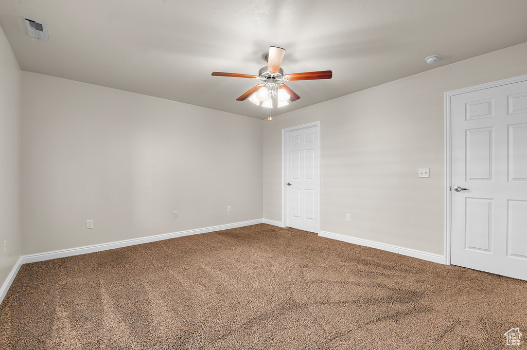 Empty room featuring carpet flooring, a ceiling fan, and a smoke detector