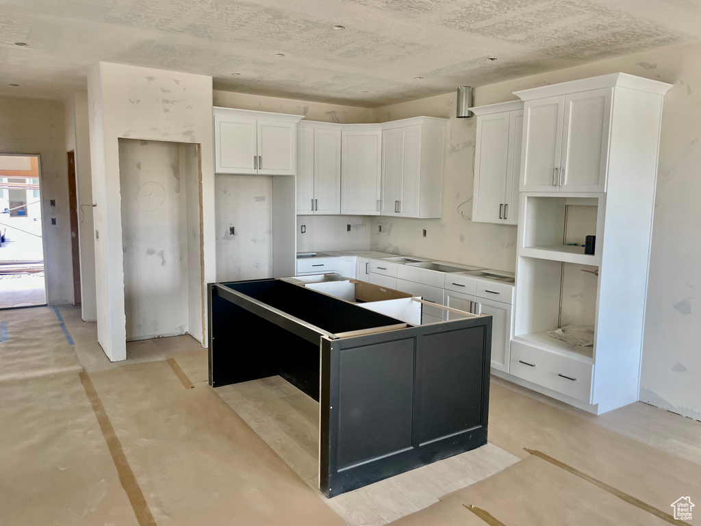 Kitchen with a center island, concrete flooring, and white cabinetry