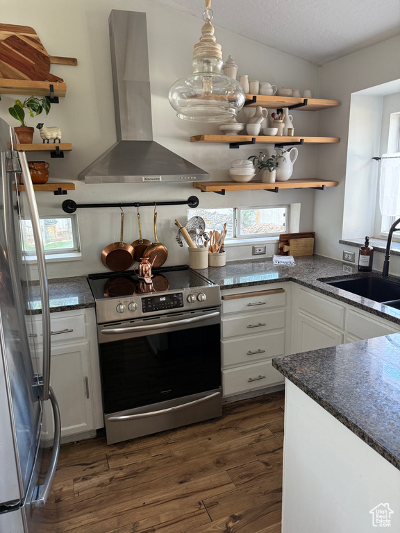 Kitchen with appliances with stainless steel finishes, wall chimney exhaust hood, dark wood-style floors, white cabinetry, and open shelves