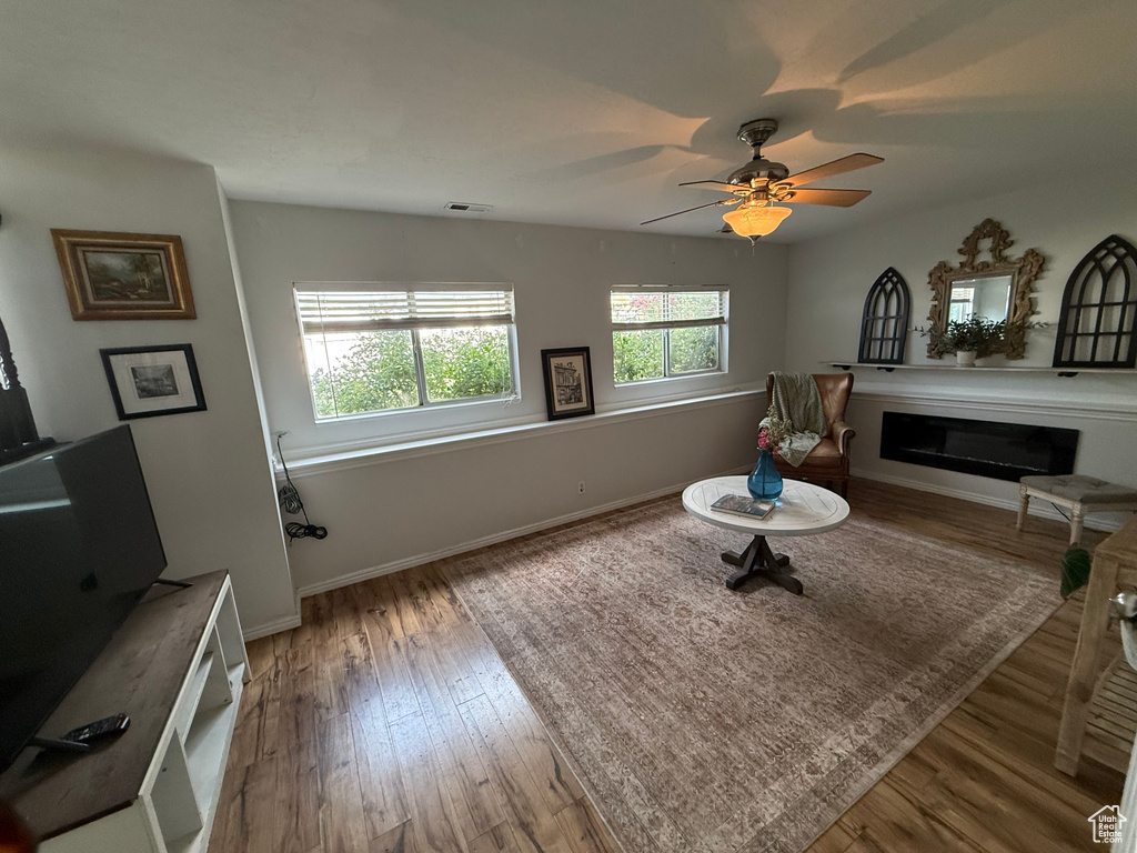 Living area featuring a fireplace, wood finished floors, and ceiling fan