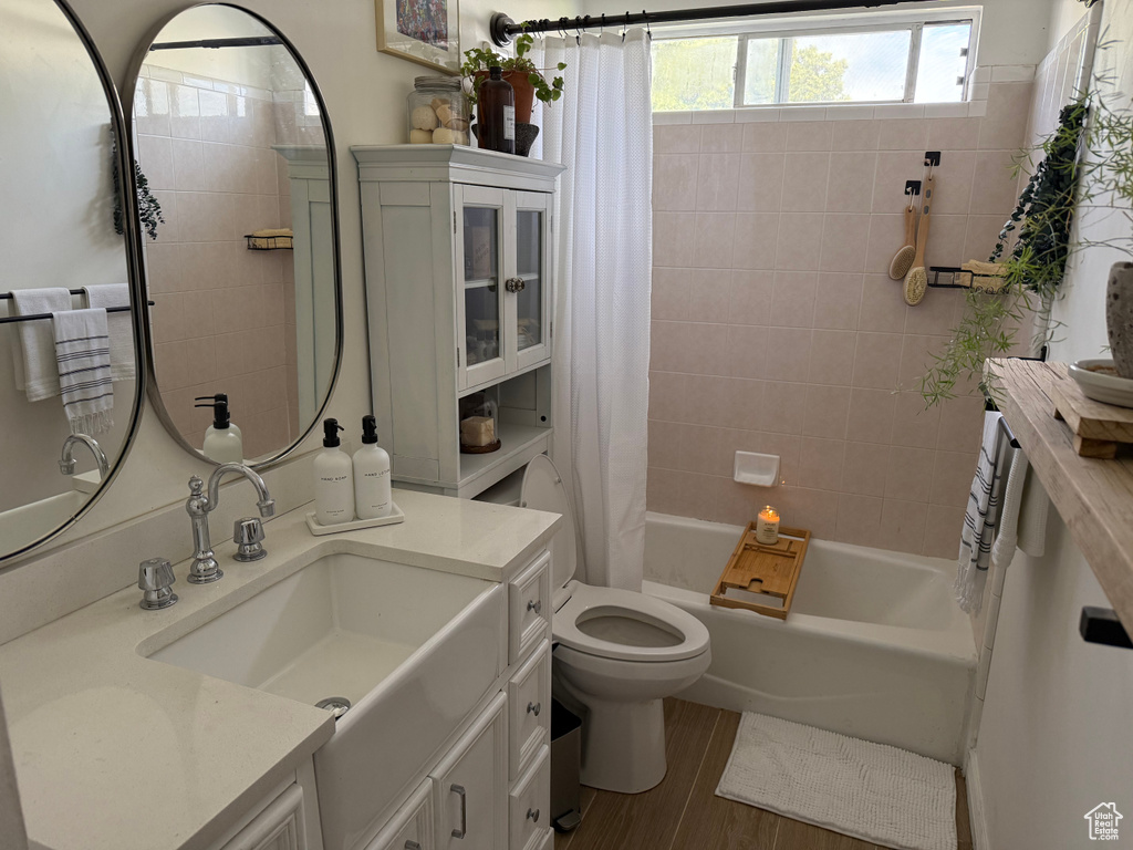 Full bath with vanity, shower / tub combo with curtain, and wood finished floors