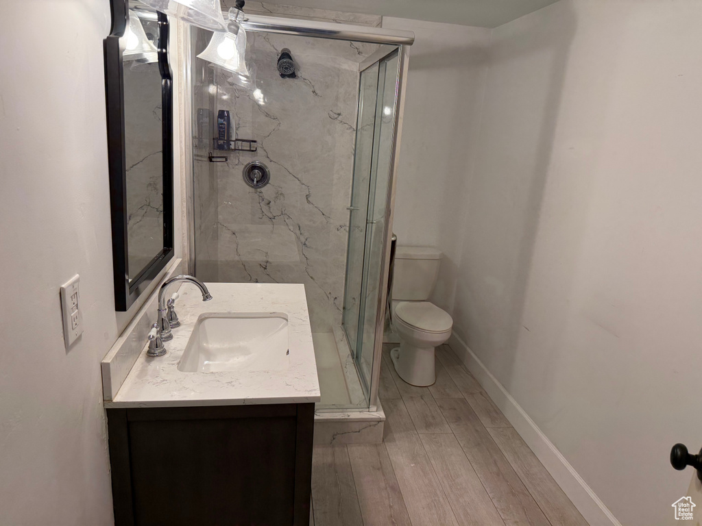 Bathroom featuring vanity, a marble finish shower, and wood finished floors