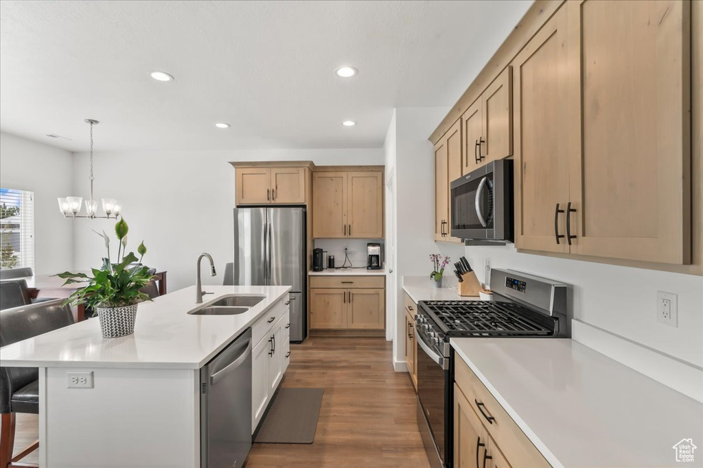 Kitchen featuring appliances with stainless steel finishes, a breakfast bar, a chandelier, light countertops, and wood finished floors
