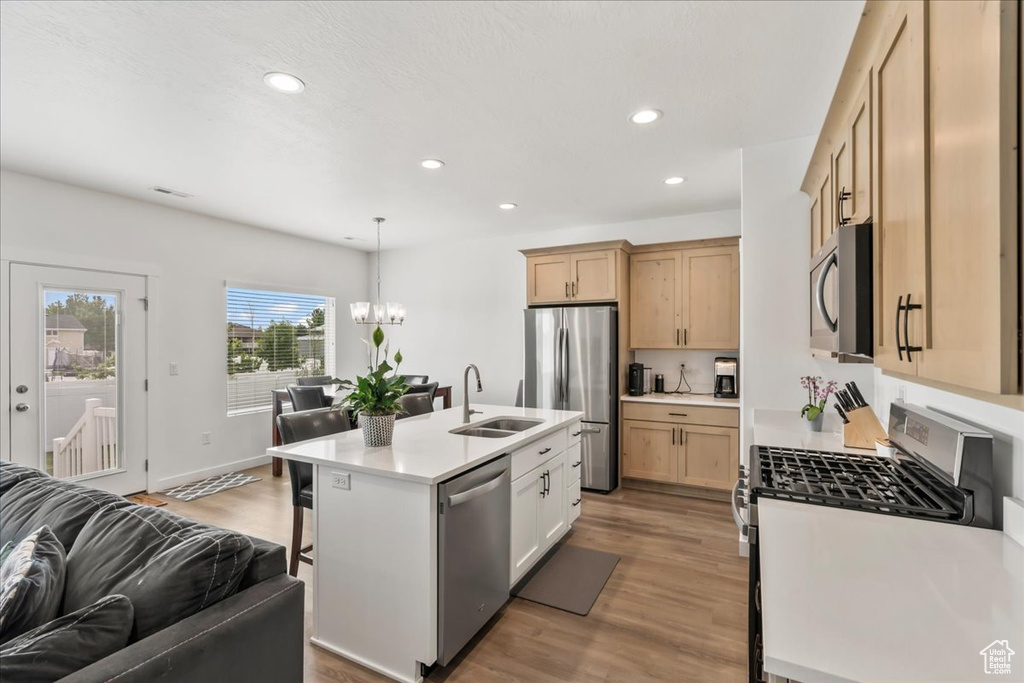 Kitchen with stainless steel appliances, open floor plan, light wood-style flooring, a breakfast bar, and a chandelier