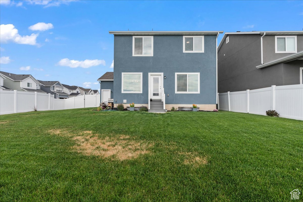 Rear view of house featuring entry steps, a fenced backyard, stucco siding, and a residential view