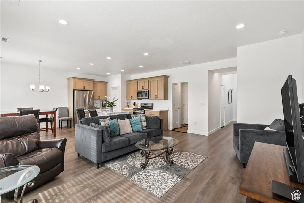 Living room with a chandelier, dark wood-type flooring, and recessed lighting