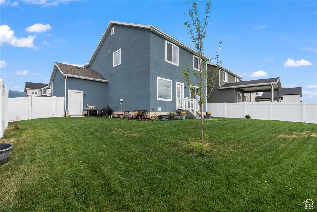 Rear view of property featuring a fenced backyard and stucco siding